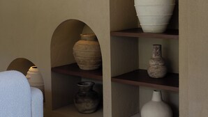 Una habitación con un sofá, una mesa de madera y estanterías con jarrones.