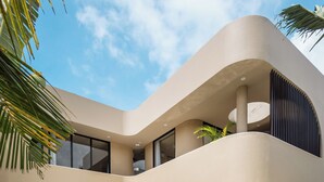 Una casa moderna con piscina, puertas de cristal amplias y un balcón.