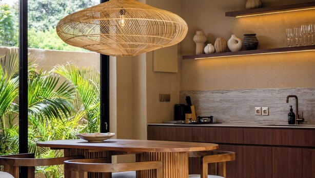Una cocina moderna con comedor, ventanas amplias y una lámpara colgante.