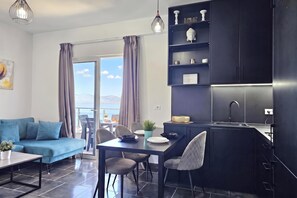 A modern living space with a sofa, dining table, chairs, and a kitchen area with cabinets and a sink. - Christine Sunny Corner 004 /w Sea View Balcony, Sarandë, Albania (Sarandë)