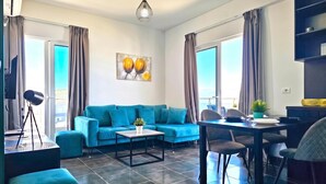 Ein modernes Wohnzimmer mit einem blauen Sofa, einem Esstisch und einem Couchtisch.