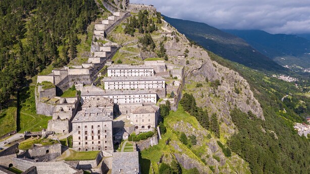 A historic stone building complex with multiple structures, situated on a hillside with a view of the surrounding landscape. - Francis Home with Balcony and Parking, Villaretto, Italy (Villaretto)