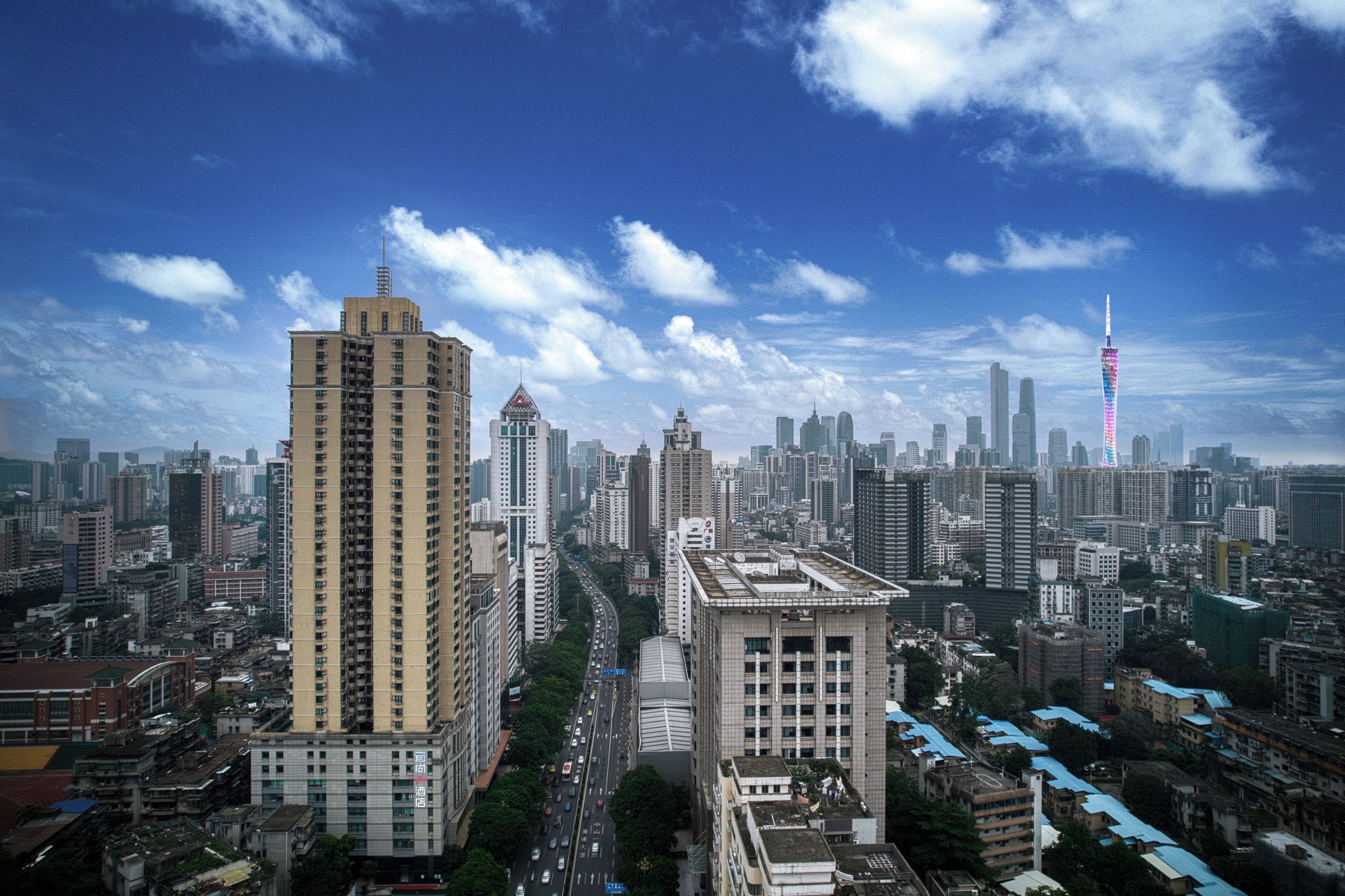 Paisagem urbana com edifícios altos, uma torre imponente com pináculo e um ambiente urbano denso.