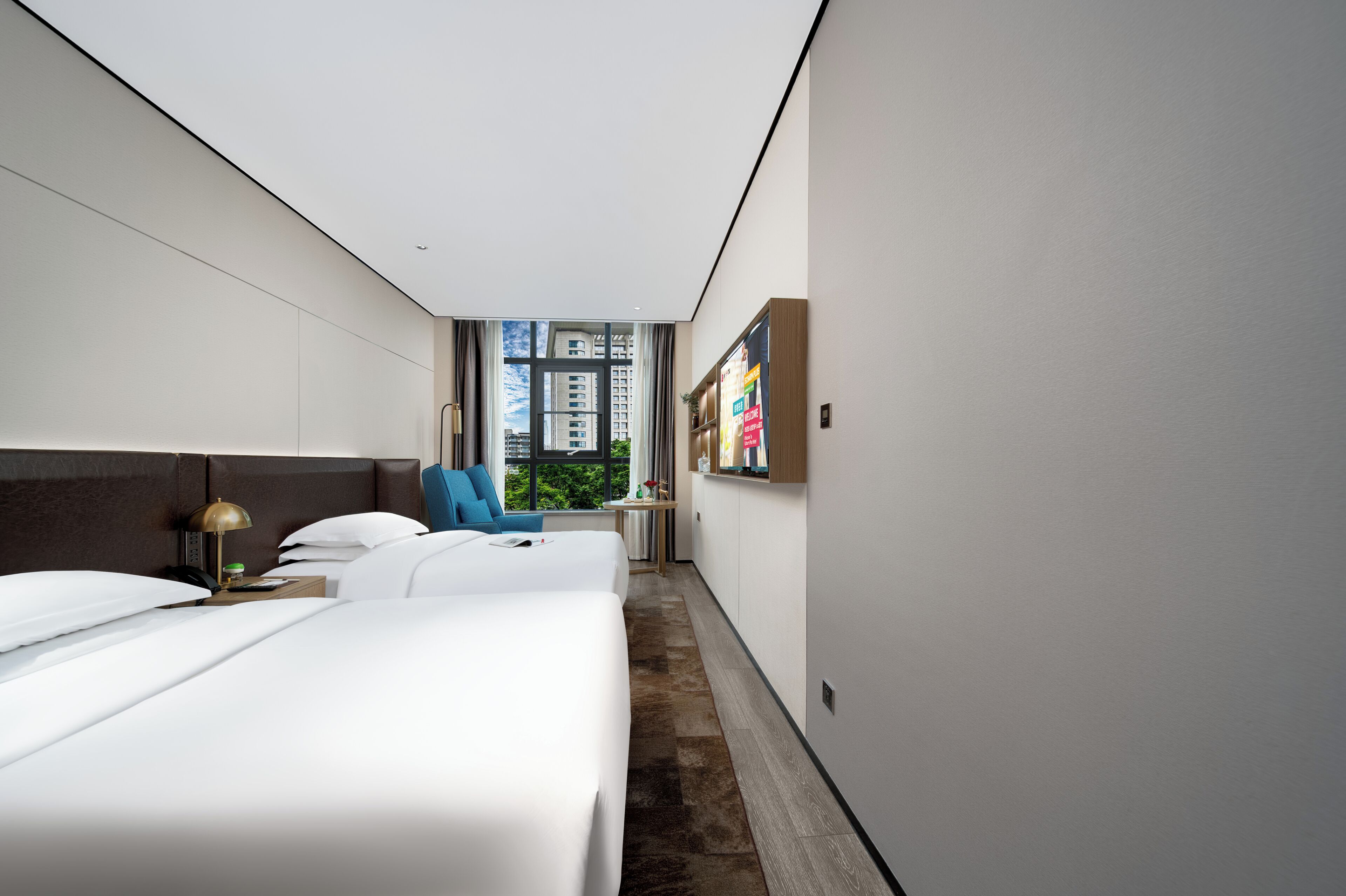 Een moderne hotelkamer met een groot bed, een bureau, een stoel en een raam met uitzicht op de stad.