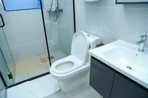 Uma casa de banho moderna com sanita, chuveiro e lavatório.