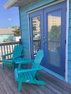 A porch with two green Adirondack chairs and a blue door with a window. - Cozy 1-bedroom on Gulf Blvd Madeira Beach, 5 min walk to John’s Pass (Madeira Beach)