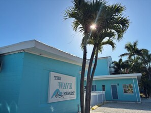 A building with a sign reading 'The Wave Resort,' surrounded by palm trees and a clear blue sky. - Cozy 1-bedroom on Gulf Blvd Madeira Beach, 5 min walk to John’s Pass (Madeira Beach)