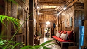 A wooden interior with a bench, a refrigerator, and a hanging light fixture.