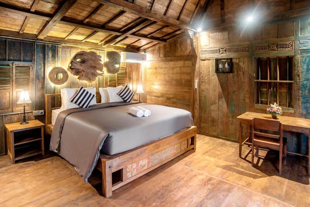 A wooden room with a bed, a desk, and a wall with decorative elements.