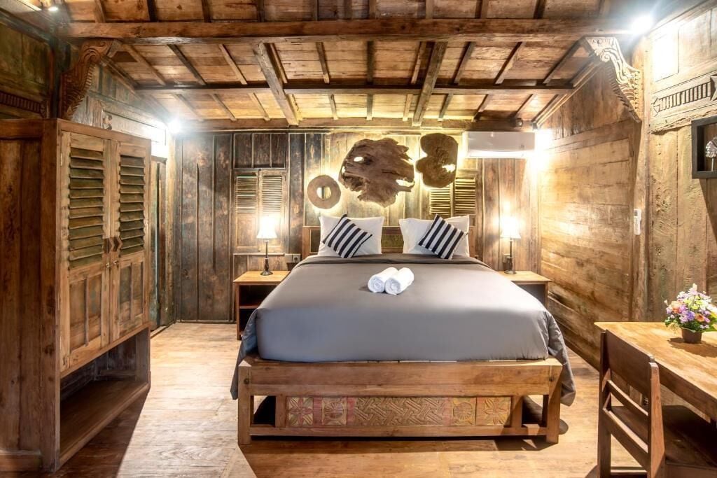 A wooden room with a bed, wooden walls, and a ceiling with exposed beams.