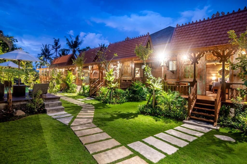 A wooden villa with a stone pathway, outdoor seating, and a well-maintained garden.