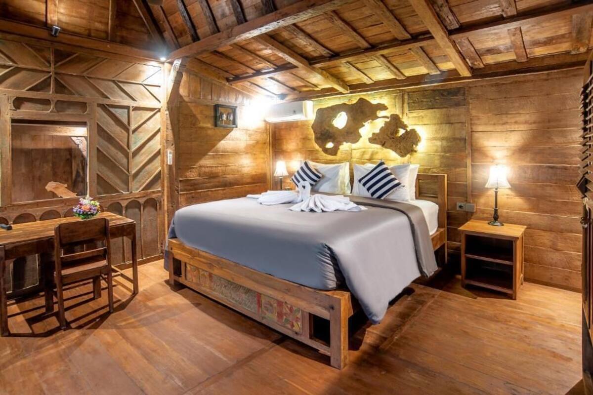 A wooden room with a bed, a desk, and a lamp.