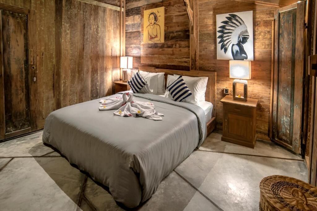 A wooden room with a bed, pillows, a nightstand, and wall art.