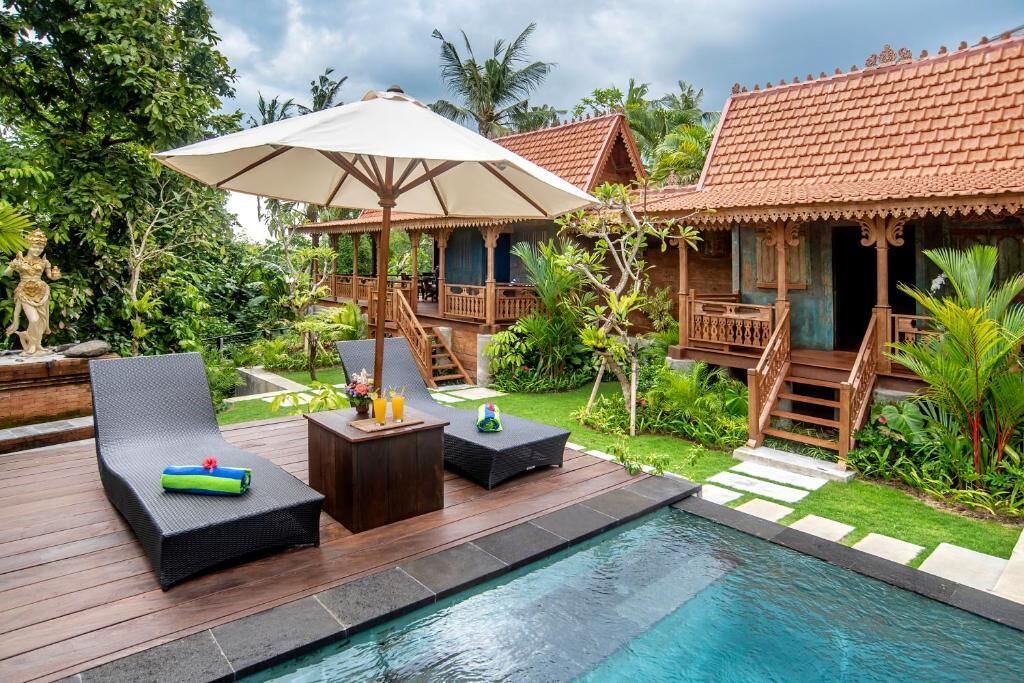 Un espace aménagé au bord de la piscine, avec des chaises longues, une terrasse en bois et un petit pavillon.
