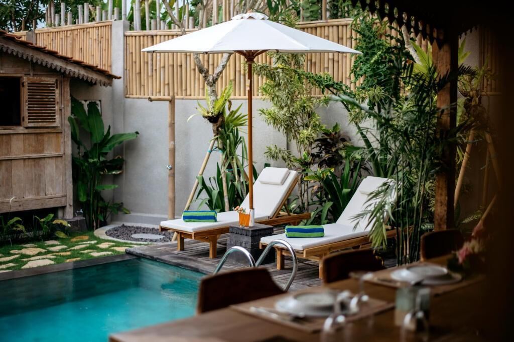 Un espace aménagé au bord de la piscine, avec des chaises longues, un parasol et une table à manger.