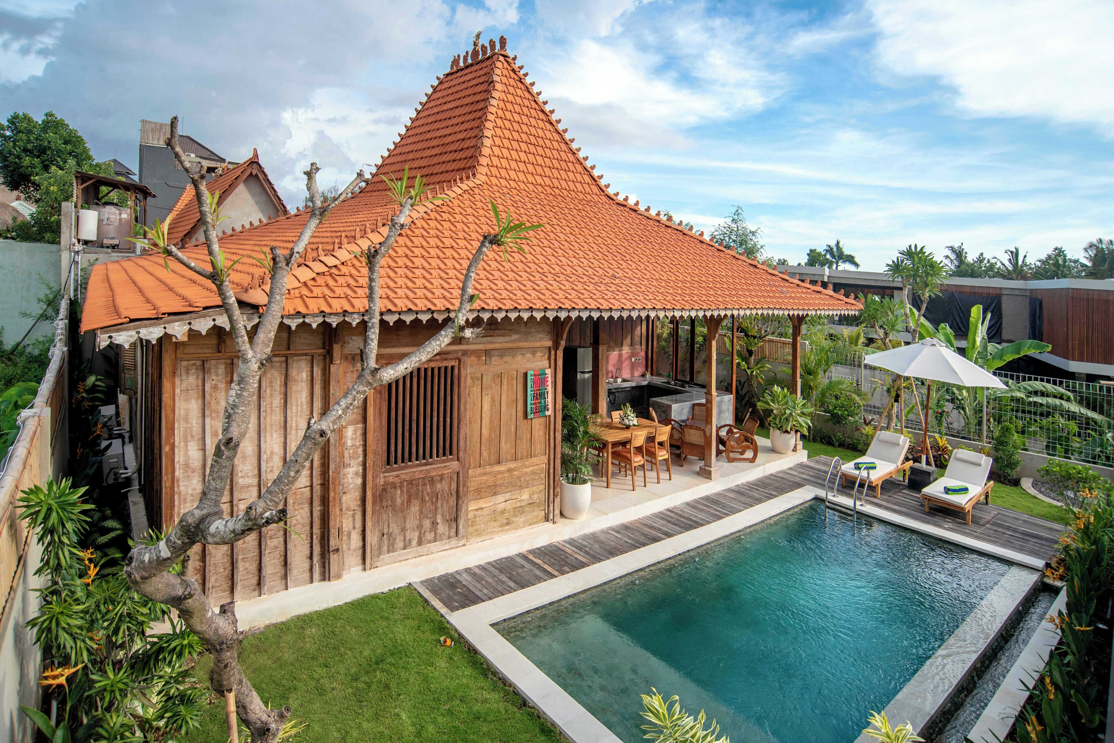 A villa with a swimming pool, wooden exterior, and a covered outdoor seating area.