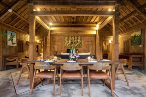 Un comedor de madera con una mesa central, sillas y un sofá.