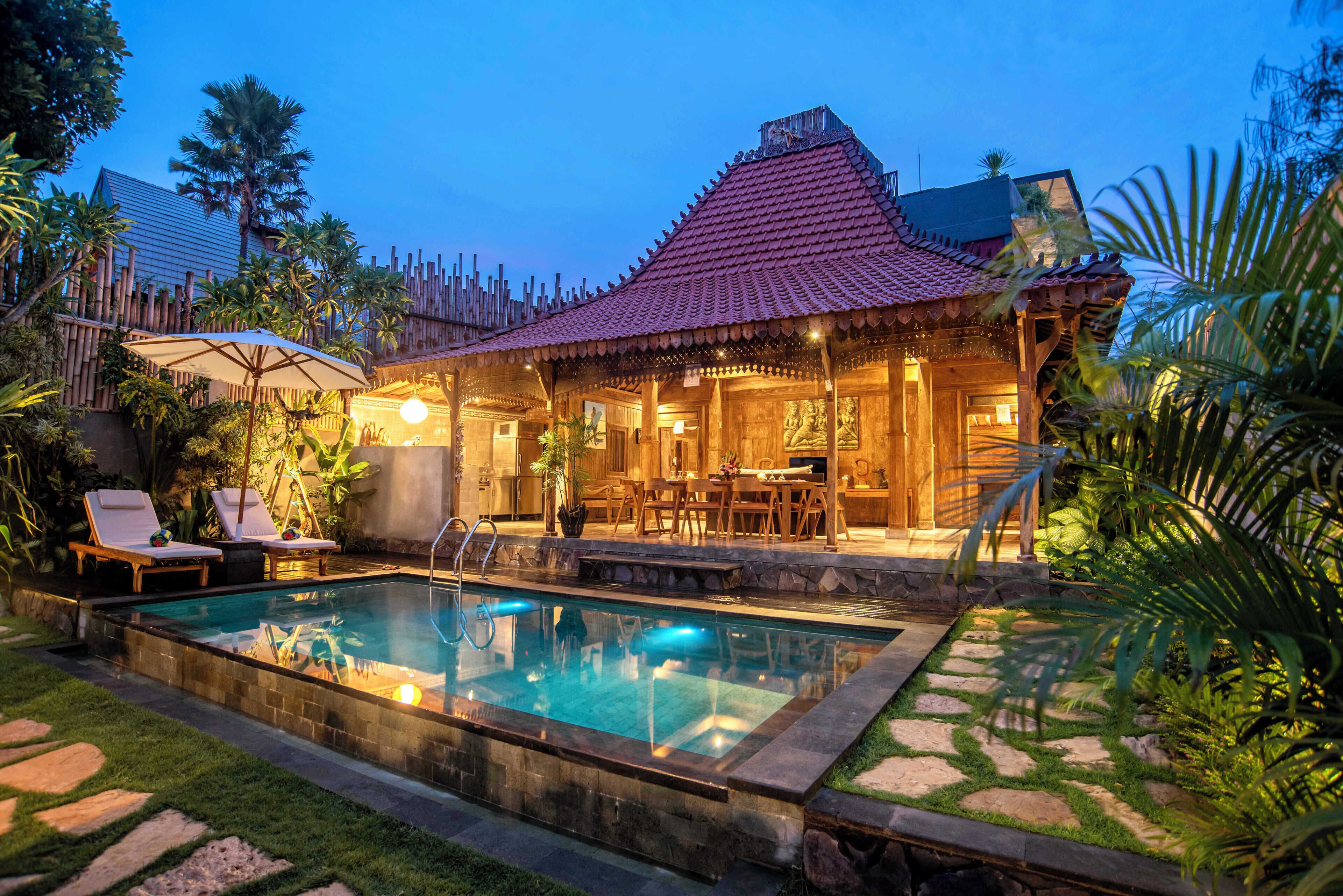 A poolside area with a tiled roof, lounge chairs, and a dining area.