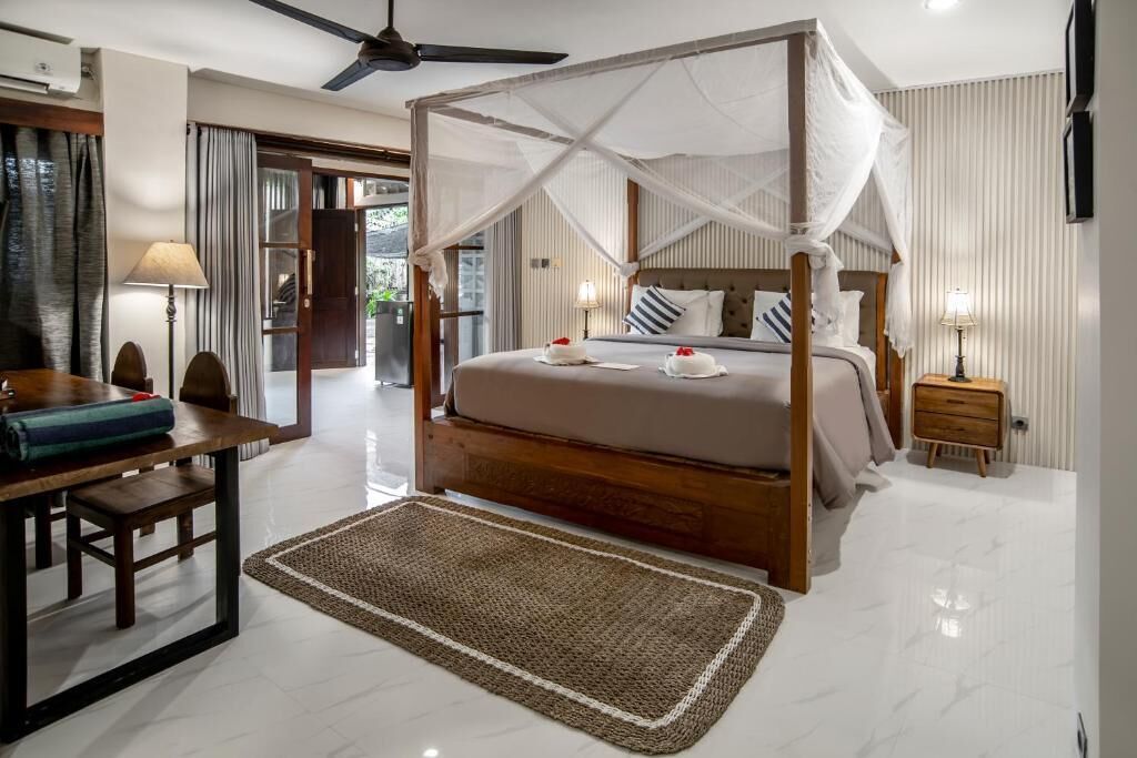 Un dormitorio con una cama con dosel, una mesita de noche de madera, un escritorio y una silla.