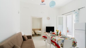 A modern living room with a brown sofa, a dining table with a colorful tablecloth, and a TV. - Villa Paradiso by Vivimy (Capilungo)