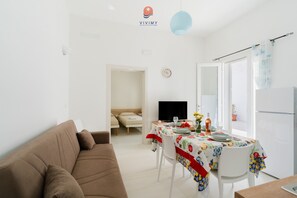 A modern living room with a brown sofa, a dining table with a colorful tablecloth, and a TV. - Villa Paradiso by Vivimy (Capilungo)