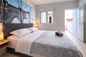 Ein Schlafzimmer mit Bett, Nachttisch, Lampe, Fenster und Tür.