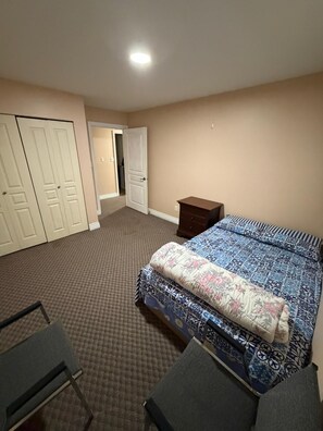 Une chambre à coucher comprenant un lit, une chaise, une table de chevet et une armoire.