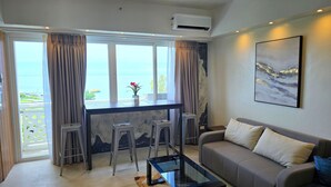 Un salon moderne avec un canapé, une table basse et une vue sur la mer grâce à de grandes fenêtres.