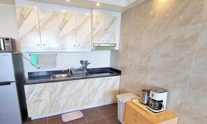 A modern kitchen with a microwave, sink, cabinets, and a coffee maker.