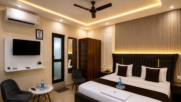 A hotel room with a bed, a TV, a desk, a chair, and a ceiling fan. - Hotel sudan inn kalka shimla higway  (Zirakpur)