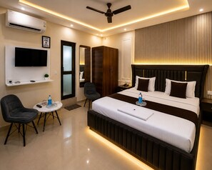 A hotel room with a bed, a TV, a desk, a chair, and a ceiling fan. - Hotel sudan inn kalka shimla higway  (Zirakpur)