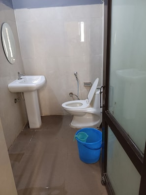 Un baño pequeño con lavamanos blanco, inodoro y un cubo azul.