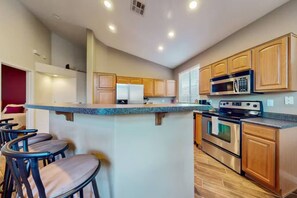 A modern kitchen with a central island, stainless steel appliances, and wooden cabinets. - The Palo Verde | Pool, Fire Pit & Fast Wi-Fi | Sleeps 8 (Phoenix)