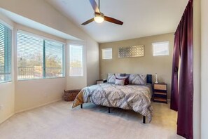 A bedroom with a bed, a ceiling fan, a nightstand, a lamp, and a window with blinds. - The Palo Verde | Pool, Fire Pit & Fast Wi-Fi | Sleeps 8 (Phoenix)