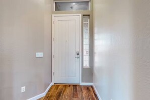 A hallway with a white door, a small window, and a light switch on the wall. - The Palo Verde | Pool, Fire Pit & Fast Wi-Fi | Sleeps 8 (Phoenix)