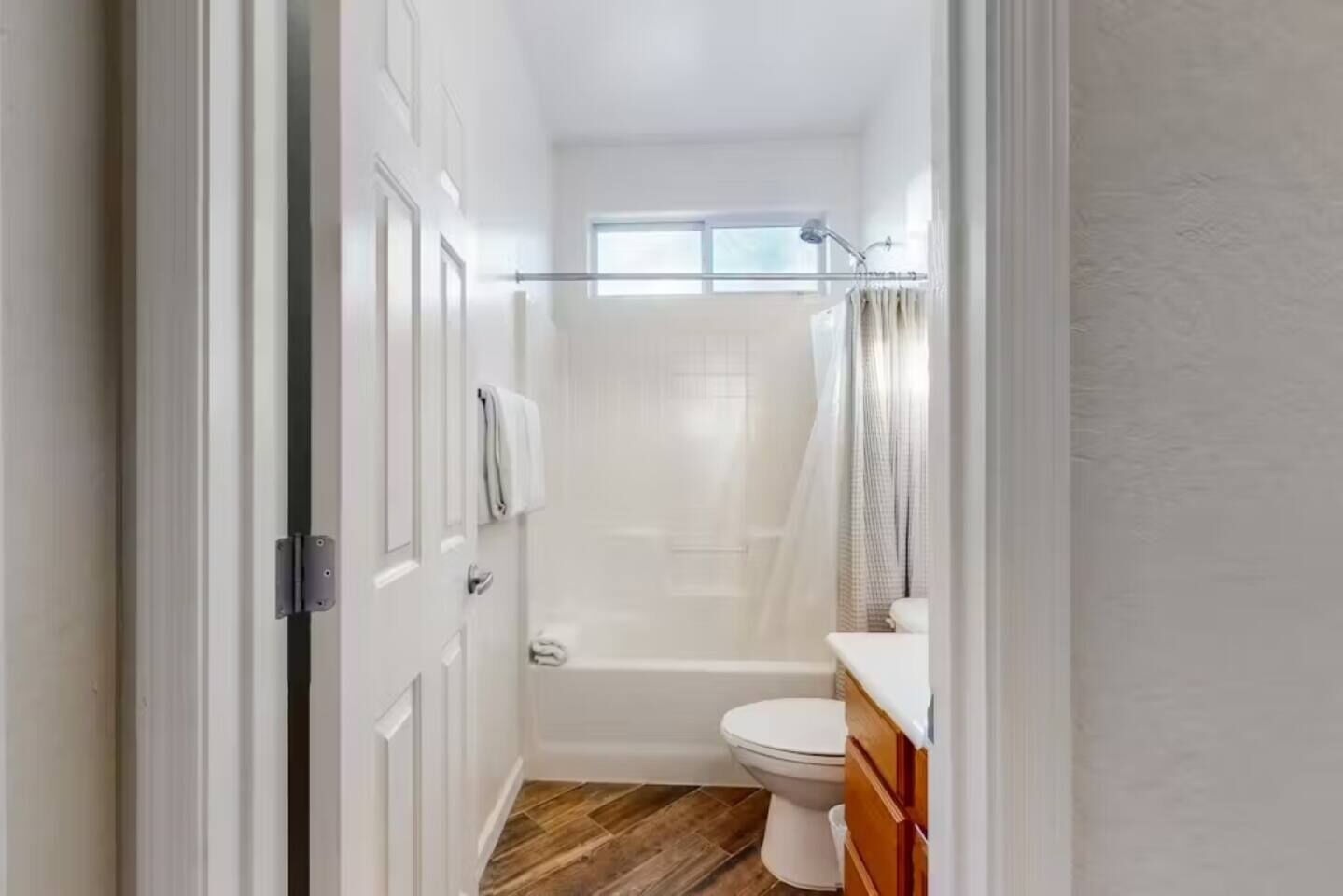 Et lille badeværelse med toilet, bruser og et vindue.