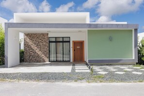 A modern house with a stone facade, a wooden door, and a green wall. - 3-bedroom house in peaceful Punta Cana with cool AC (Punta Cana)
