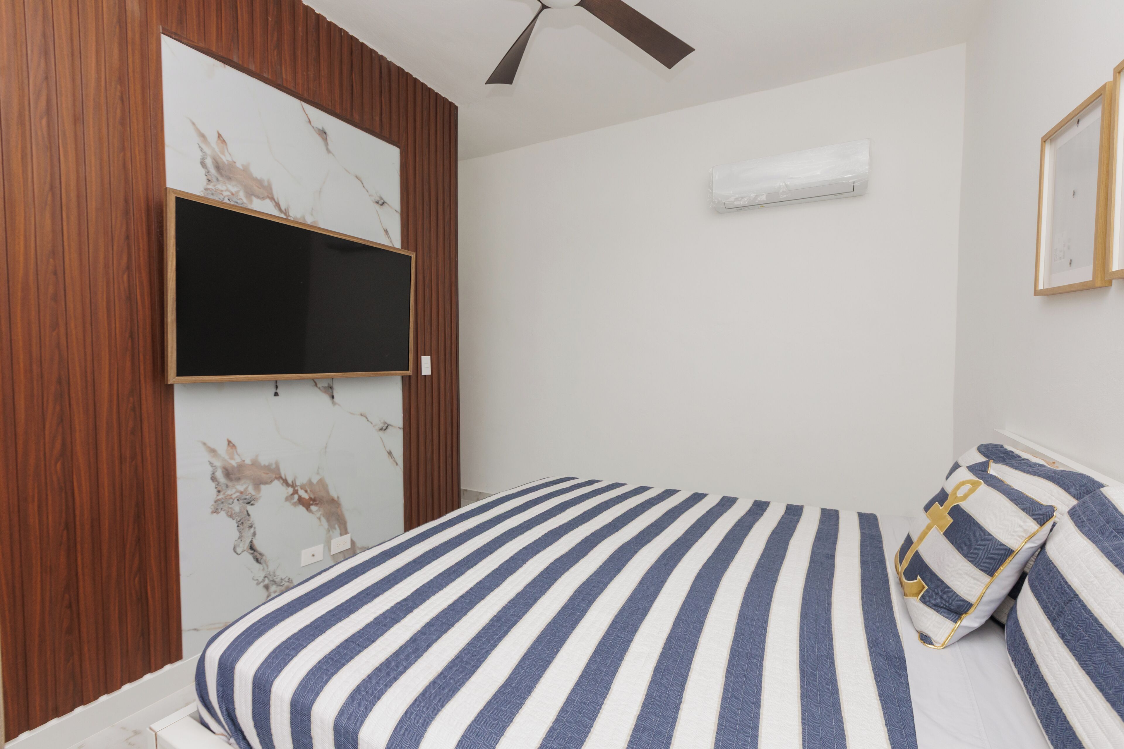 Una camera da letto con un letto, pannelli in legno, una TV a parete e un condizionatore.