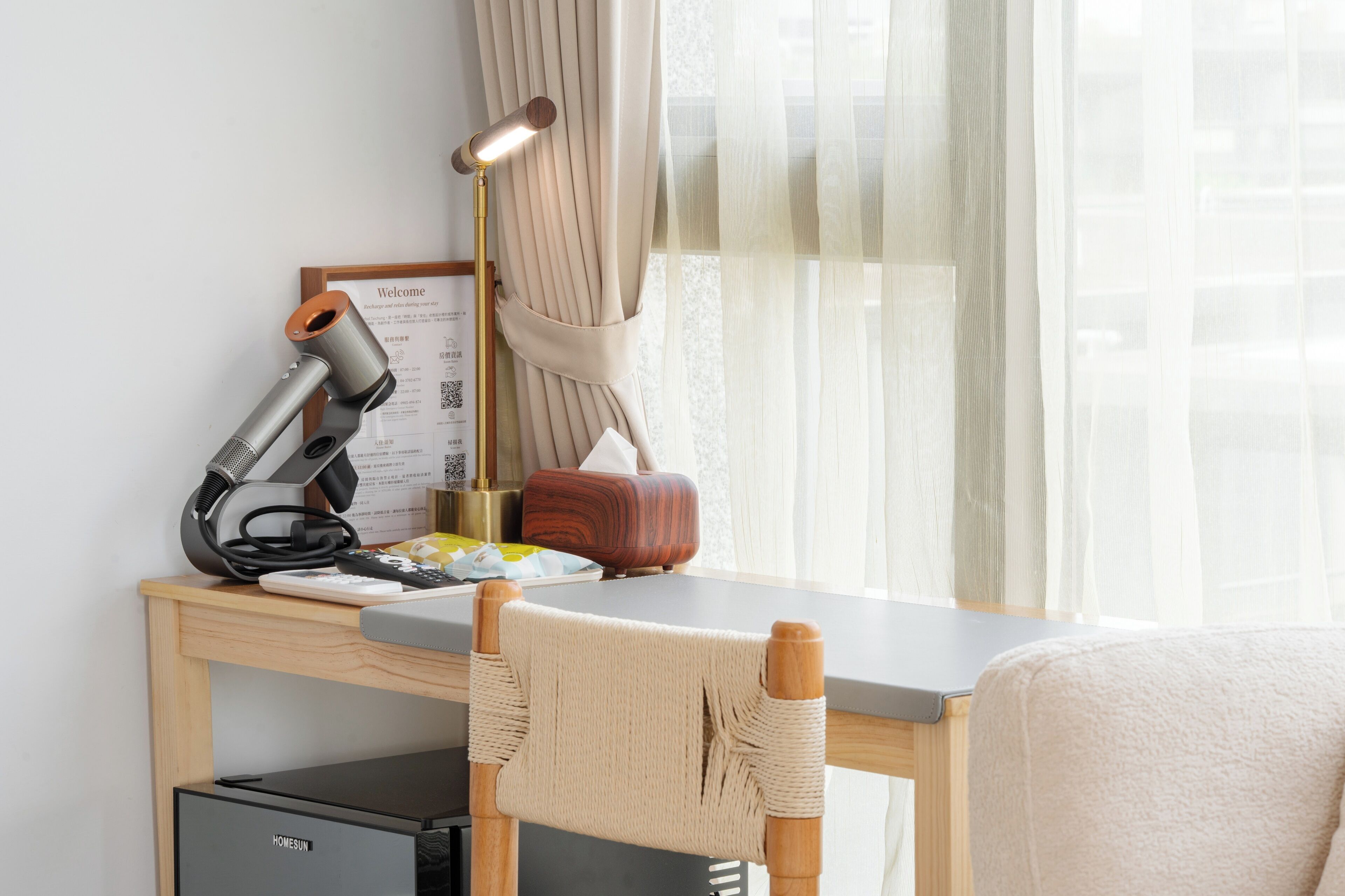 Une chambre d’hôtel équipée d’un bureau, d’une lampe, d’une radio, d’une chaise et d’un lit.