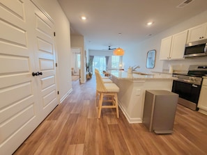Une cuisine moderne avec un plancher en bois, des meubles blancs et un îlot central.