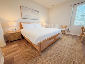 Une chambre à coucher avec un lit, des tables de chevet, un radiateur, une chaise et une fenêtre avec des rideaux.