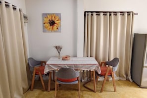 Ein Essbereich mit Tisch, Stühlen, einem Sonnenblumenbild und Vorhängen.
