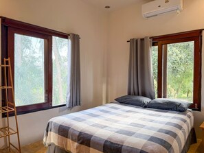 A bedroom with a bed, two windows with curtains, a wooden ladder, and an air conditioning unit. - Sunset View - Home near Beach (300m.) - 2 BR (ตำบลเกาะพะงัน)