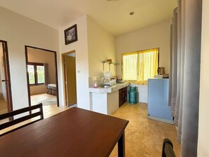 A compact kitchen with a dining table, a small island, and a refrigerator. - Sunset View - Home near Beach (300m.) - 2 BR (ตำบลเกาะพะงัน)