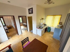 A compact kitchen with a dining area, a small island, and a view of a bedroom. - Sunset View - Home near Beach (300m.) - 2 BR (ตำบลเกาะพะงัน)