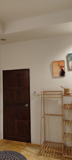 Ein Zimmer mit Holztür, einer Wandregal mit Körben und einem gemusterten Teppich.