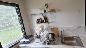 Une cuisine moderne équipée d’une cuisinière intégrée, d’un évier et d’une étagère en verre où sont rangés des ustensiles de cuisine.