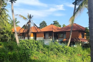 Ein bungalowähnliches Gebäude mit einem Ziegeldach, umgeben von üppiger Vegetation und Palmen.