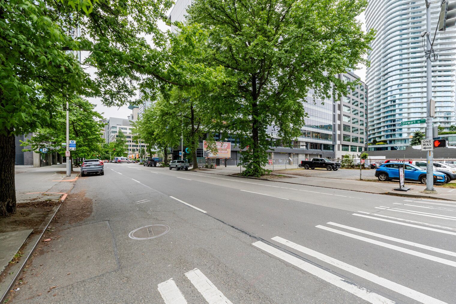Eine Stadtstraße mit Zebrastreifen, parkenden Autos und modernen Gebäuden.