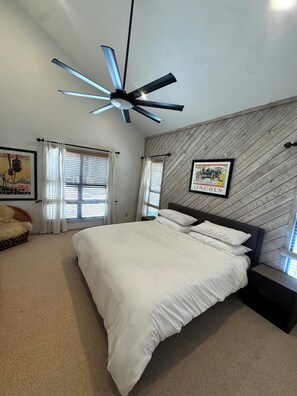 A bedroom with a bed, a ceiling fan, a wooden wall panel, and a framed picture. - Walk to Eagle Lodge from this Cozy 2 Bedroom Condo (Mammoth Lakes)